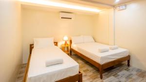 Cette petite chambre comprend deux lits et une lampe. dans l'établissement ALONA BEACH SIDE INN, à Panglao