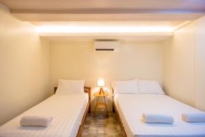 two twin beds in a small room with a lamp at ALONA BEACH SIDE INN in Panglao