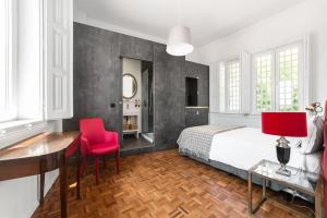 1 dormitorio con cama, escritorio y sillas rojas en Monte Belvedere Hotel by Shiadu en Lisboa