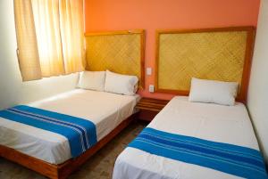 2 letti in una camera con pareti arancioni di HOSTAL CHOCOLATE CALENDA a Città di Oaxaca Altre 37 foto
