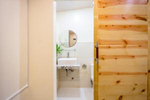 baño con puerta de madera y lavamanos en ALONA BEACH SIDE INN, en Panglao