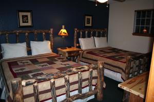 a bedroom with two beds and a table with a lamp at Timber Creek Chalets- 12 chalet in Estes Park
