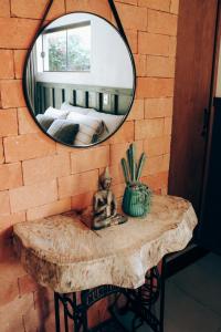 a mirror on a brick wall with a table with a statue at Studio Bougainville - Praia do Rosa in Imbituba