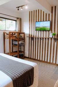 a bedroom with a bed and a flat screen tv at Studio Bougainville - Praia do Rosa in Imbituba