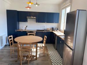 a kitchen with blue cabinets and a table and a refrigerator at joli duplex centre ville 5 min à pied de la gare sncf in La Loupe +8 photos