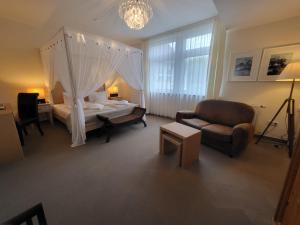 ein Schlafzimmer mit einem Bett, einem Sofa und einem Stuhl in der Unterkunft Naturhotel Baltrum in Baltrum