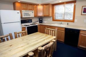 cocina con mesa de madera y nevera blanca en Timber Creek Chalets- 9 chalet, en Estes Park