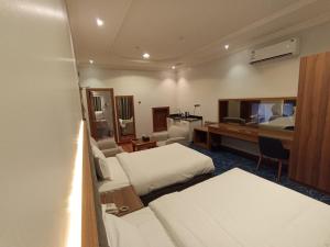Habitación de hotel con 2 camas y escritorio en الماسم للأجنحة المخدومة- الملك فهد, en Riad