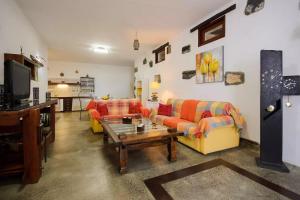 a living room with orange and yellow couches and a table at Apartamento Los 4 Nobles in Tinajo