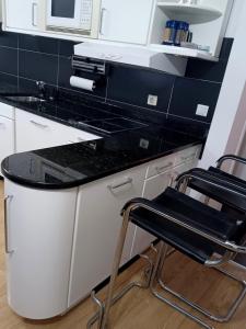 a kitchen with a black counter top and two stools at Desperado in Slavonski Brod