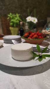 a white cake on a table with a bowl of strawberries at Antica Locanda Lunetta in Màndas