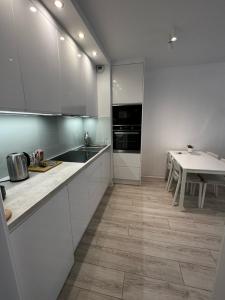 a kitchen with white cabinets and a table at Flat4You IV in Poznań