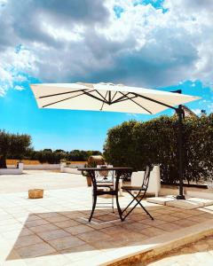 een tafel en stoel onder een parasol op een patio bij Trulli Mamima in Martina Franca