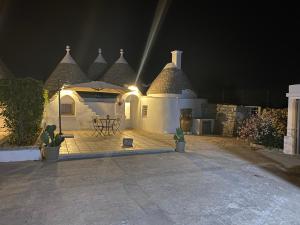 a house with a table and an umbrella at night at Trulli Mamima in Martina Franca