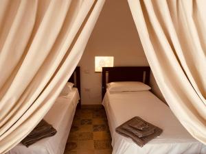 two beds in a room with curtains at Trulli Mamima in Martina Franca