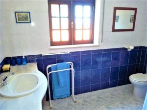 W wyłożonej niebieskimi kafelkami łazience znajduje się umywalka i toaleta. w obiekcie Vivienda en la playa de los surfistas! Baleal-Portugal - Hasta 11 PAX w mieście Ferrel
