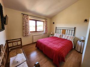 1 dormitorio con 1 cama con manta roja y ventana en El Torreon II, en Hoyos del Espino