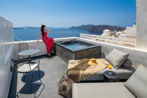 a woman in a red dress standing on a balcony at Imerti Suites in Oia