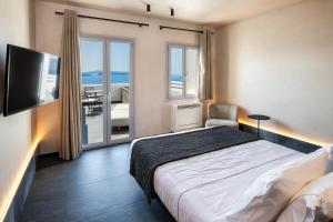 a bedroom with a bed and a television and a balcony at Imerti Suites in Oia