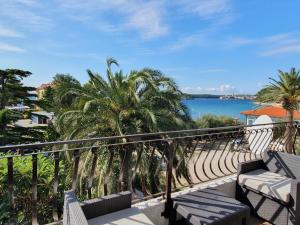 a balcony with palm trees and a view of the water at Apartments Flora 1 in Rab