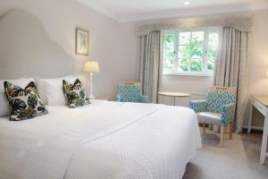 um quarto com uma grande cama branca e cadeiras em Manor House Hotel & Spa, Alsager em Alsager