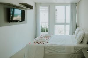 a white bedroom with a bed with red roses on it at Wave Suítes Hotel & Lounge bar in Maceió
