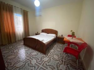 a bedroom with a bed and a red chair at Guest House Sherifi Berat in Berat