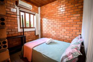 Habitación pequeña con cama en una pared de ladrillo en Pousada Natureza, en Florianópolis