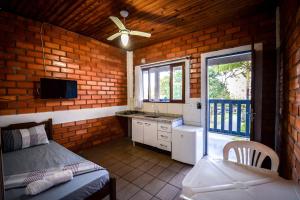 1 dormitorio con 1 cama y cocina con ventilador de techo. en Pousada Natureza, en Florianópolis