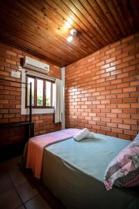 1 dormitorio con 1 cama en una pared de ladrillo en Pousada Natureza, en Florianópolis