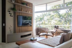 uma sala de estar com um sofá, uma televisão e uma janela em Casa com Jacuzzi Vista Mar no Campeche P2299 em Florianópolis