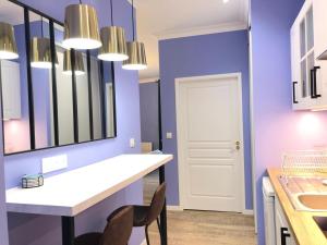 baño con paredes moradas y tocador con espejo en Suite Bubbles Spa - Luxe - Centre Ville - calme - wifi, en Troyes