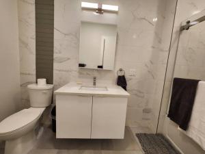 Baño blanco con aseo y lavamanos en Deluxe 2 Bedroom VIP to NYC en Union City