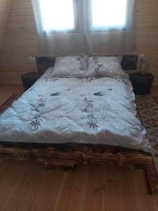 uma cama com um edredão branco e duas janelas em Cazare La Nea Marin A Frame em Ciobotani