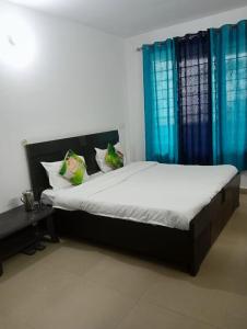 een slaapkamer met een groot bed en blauwe gordijnen bij SANDAL HOMESTAY in Kasauli