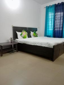 een slaapkamer met een bed met blauwe gordijnen en een tafel bij SANDAL HOMESTAY in Kasauli