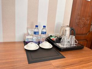 Hotel Ishonch في سمرقند: صينية عليها صحون وزجاجات ماء على طاولة