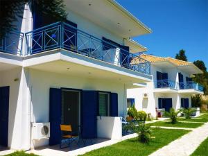 una casa bianca con porte blu e balcone di Nymphs Rooms & Apartments a Nikiana