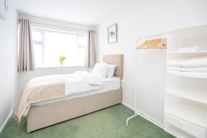 Spacious 5 Bedroom House - Sleeps 7 - 3-Car Driveway - Work - Leisure في ولفرهامبتون: غرفة نوم بيضاء بها سرير ونافذة