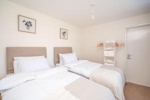 two beds in a room with white sheets at Spacious 5 Bedroom House - Sleeps 7 - 3-Car Driveway - Work - Leisure in Wolverhampton