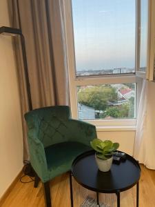 a green chair and a table in front of a window at Plaza extra lux apartman garage free in Stanovo