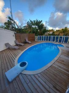 ein blauer Pool auf einer Holzterrasse mit Stühlen in der Unterkunft Bungalow Bougainvilliers in Sainte-Anne