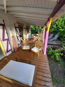 eine Veranda mit Stühlen und einer Hängematte im Haus in der Unterkunft Bungalow Bougainvilliers in Sainte-Anne