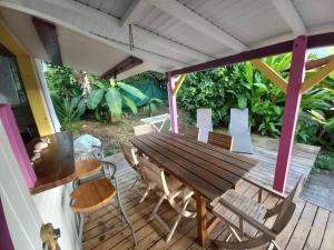 ein Holztisch und Stühle auf einer Terrasse in der Unterkunft Bungalow Bougainvilliers in Sainte-Anne