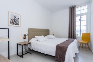 een witte slaapkamer met een bed en een stoel bij Villa Dulce Celestino Lanzarote in Nazaret +38 foto's