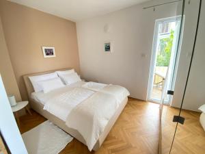 a bedroom with a white bed and a glass door at Apartments Flora 2 in Rab
