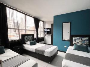 a bedroom with two beds and a blue wall at Hotel HILLS BOGOTA in Bogotá