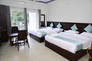 a bedroom with two beds and a table and chairs at Grand Misty Heaven in Madikeri