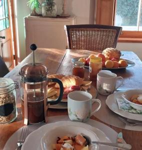 a table with a plate of food and cups of coffee at 6 Olives B&B in Darling