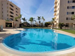 a large blue swimming pool in front of a building at LA MARINA in Torre del Mar